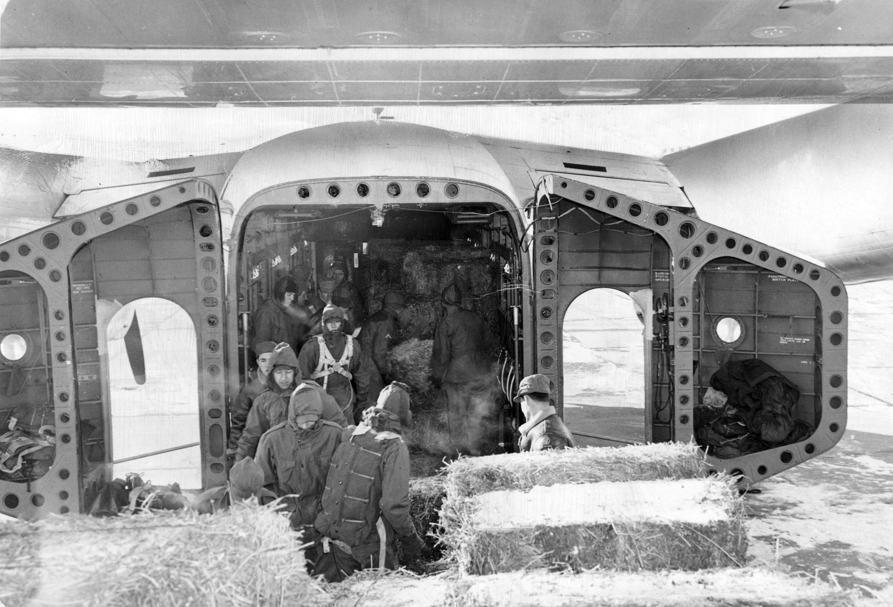 A ground crew assisted by Kearney Civil Air Patrol members load baled hay into a plane for emergency haylift in early 1949.